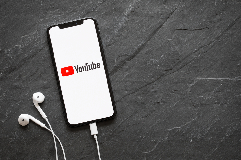 A phone with YouTube loaded on the screen with headphones plugged in.