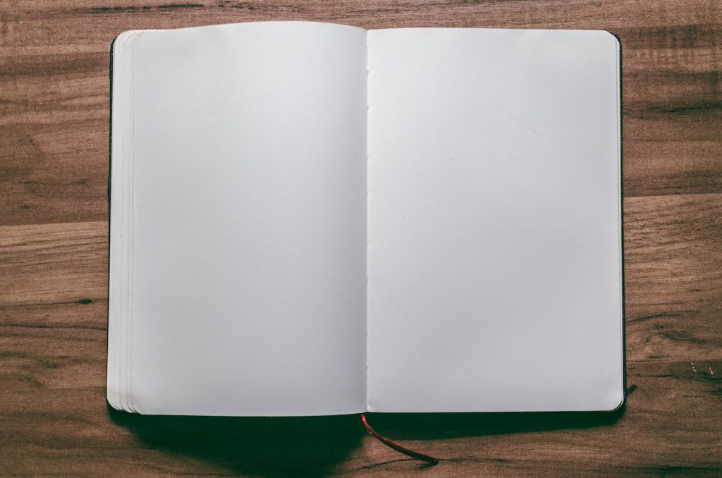 An open, blank notebook on a wooden table. 