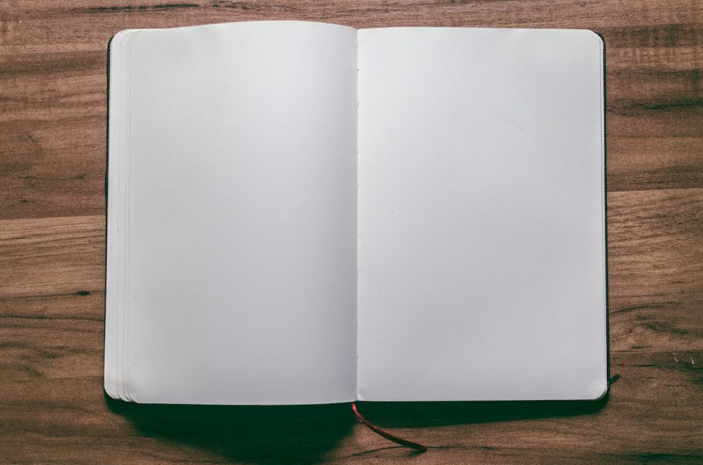An open, blank notebook on a wooden table.